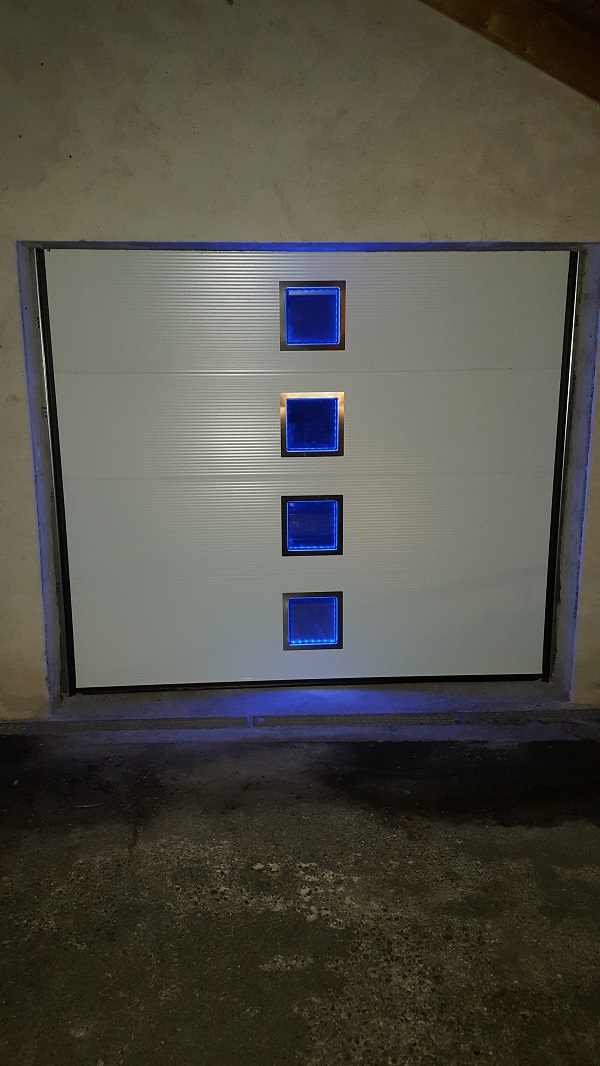 Toranlage in Umbra RAL 9016 mit Fensterausschnitten eingefasst in Edelstahl und
integrierter LED-Beleuchtungstechnik, Farbauswahl oder Durchlauf über Fernbedienung einstellbar